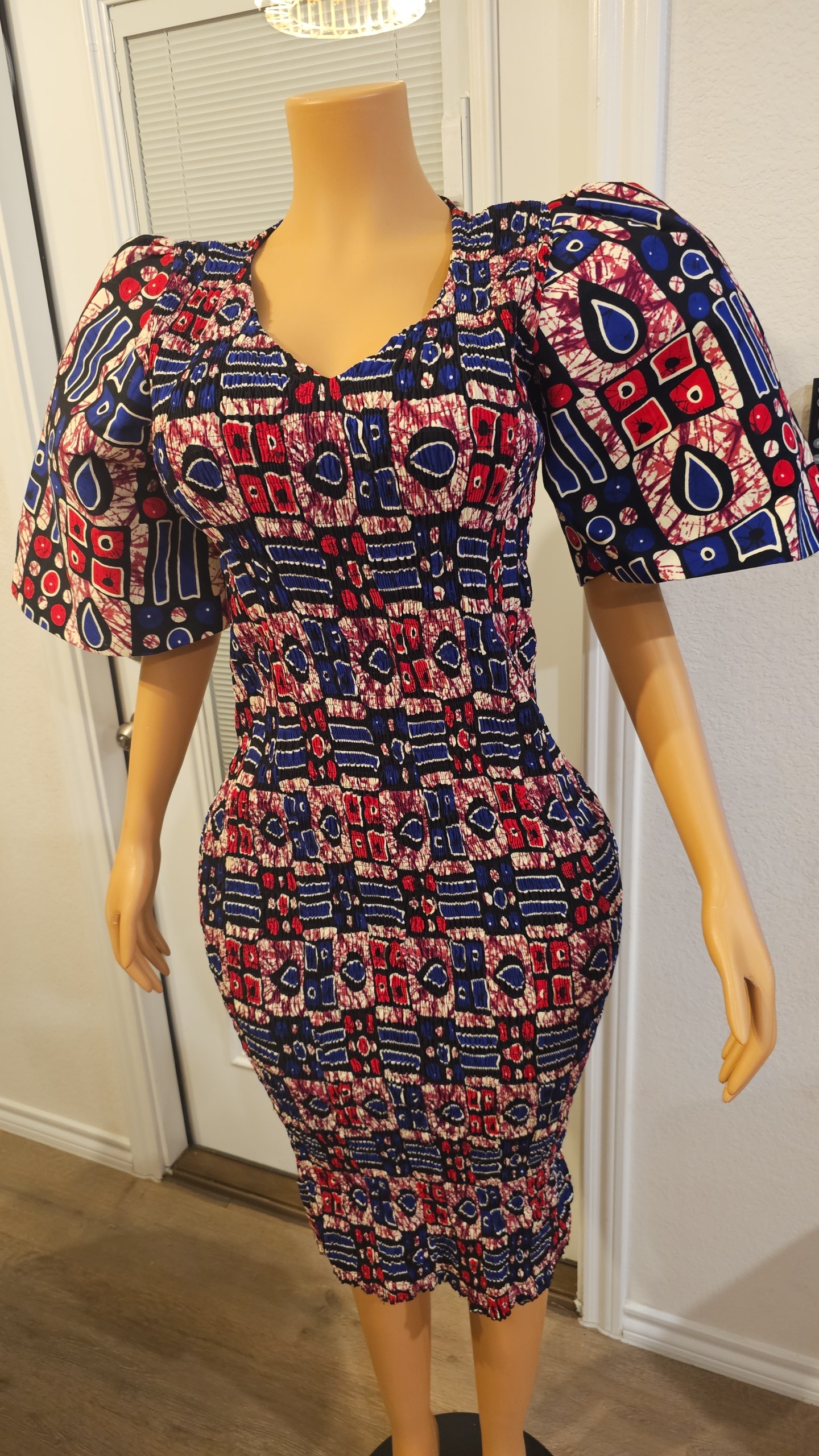 Model wearing a smokey Ankara dress featuring rich muted tones, bold African print, and a flowing, elegant silhouette